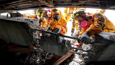 Firefighters break a concrete column blocking a rescue line in a collapsed building
